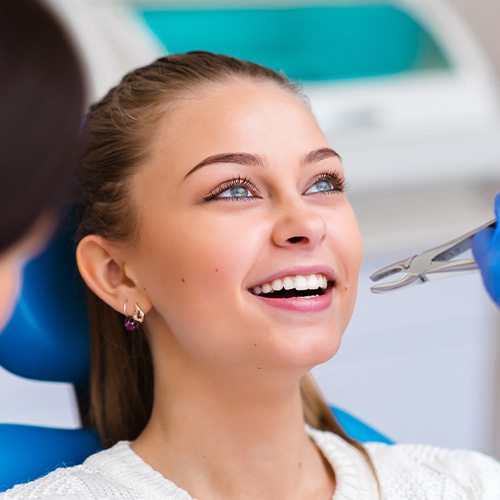 Dentist wearing blue gloves preparing to extract a woman’s tooth