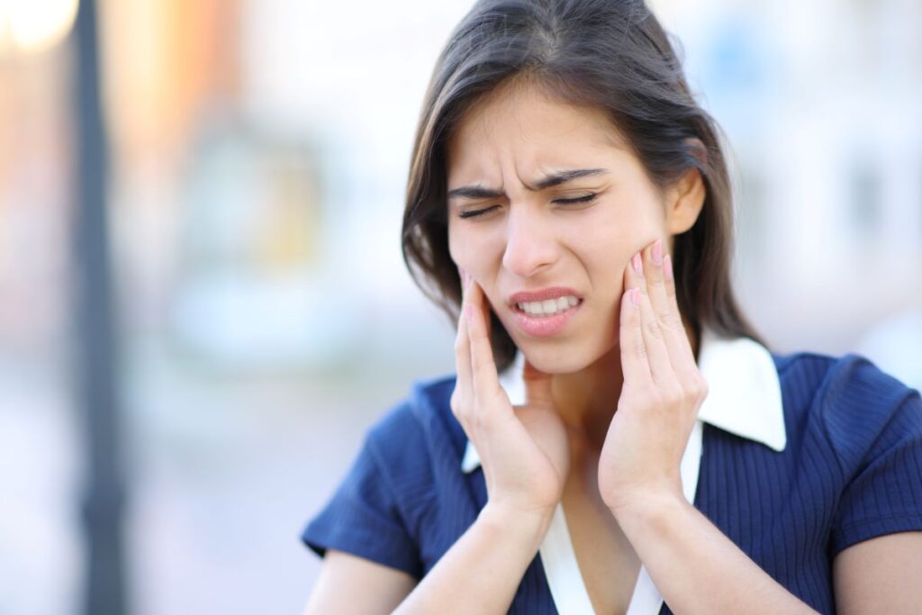 Teenage girl holding her jaw in pain